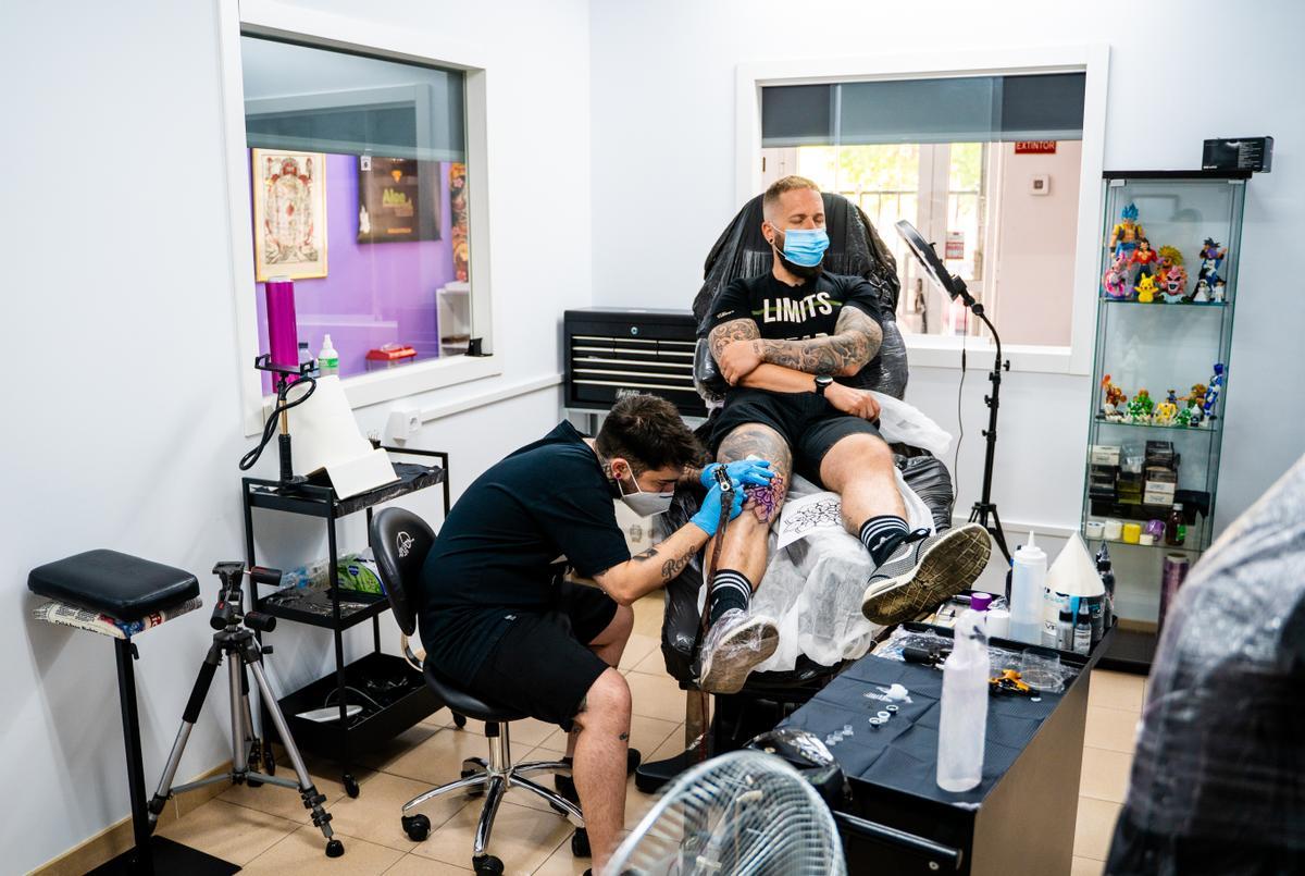 El tatuador profesional gaditano, con un cliente en su estudio.
