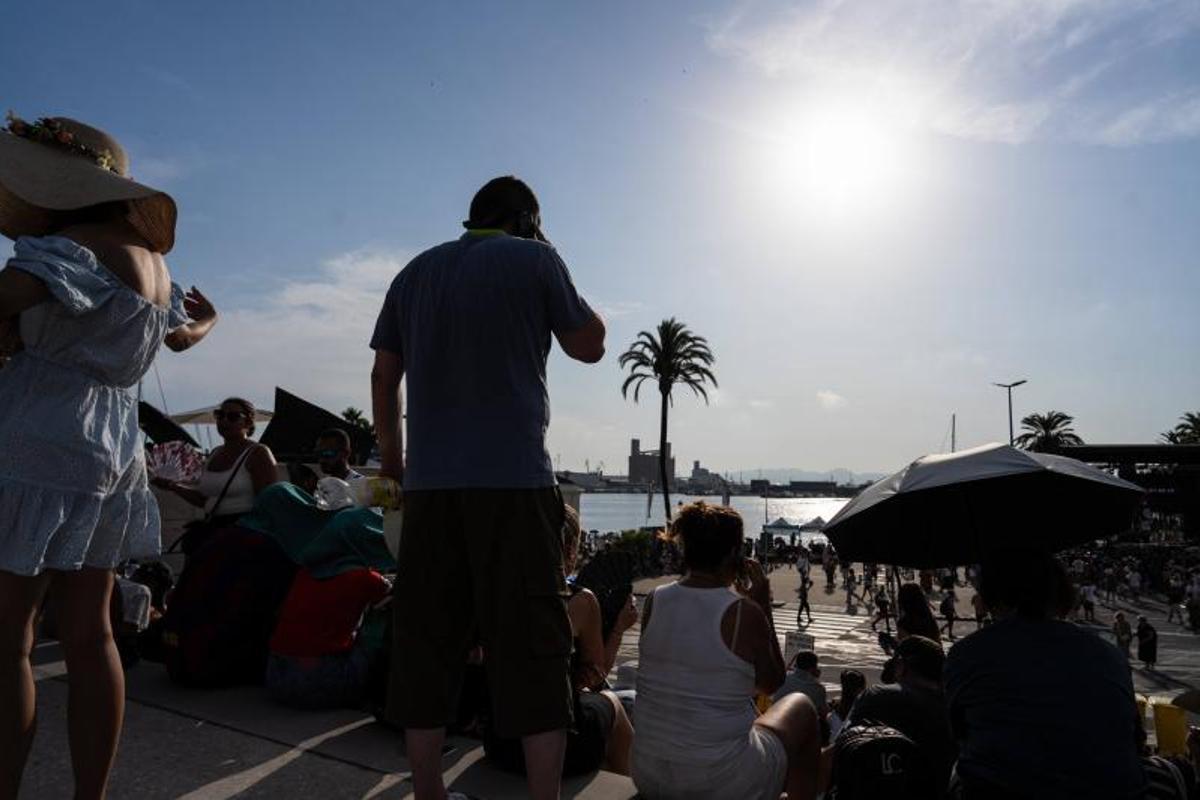Visitantes y aficionados a la observación astronómica esperan en el Port de la Maria, en Tarragona, para contemplar el eclipse total de Sol.