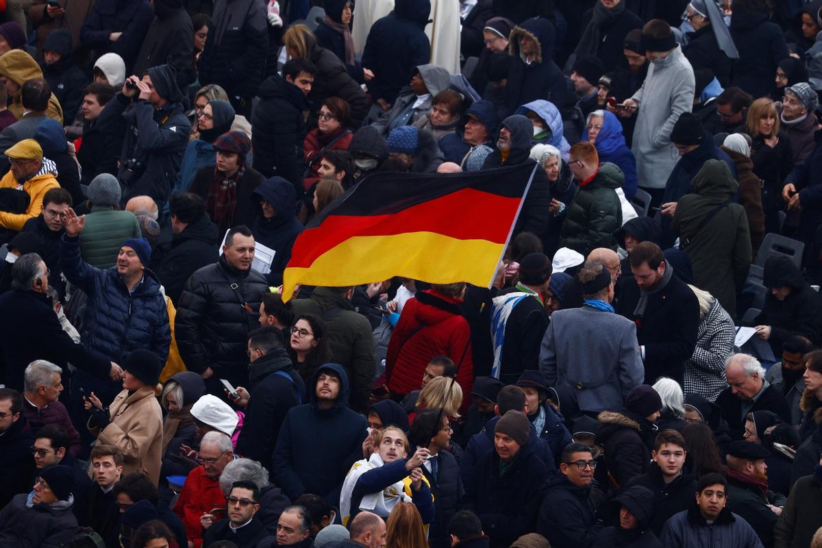 Un fiel sostiene una bandera de Alemania mientras la gente se reúne en la Plaza de San Pedro el día del funeral del ex Papa Benedicto en el Vaticano.