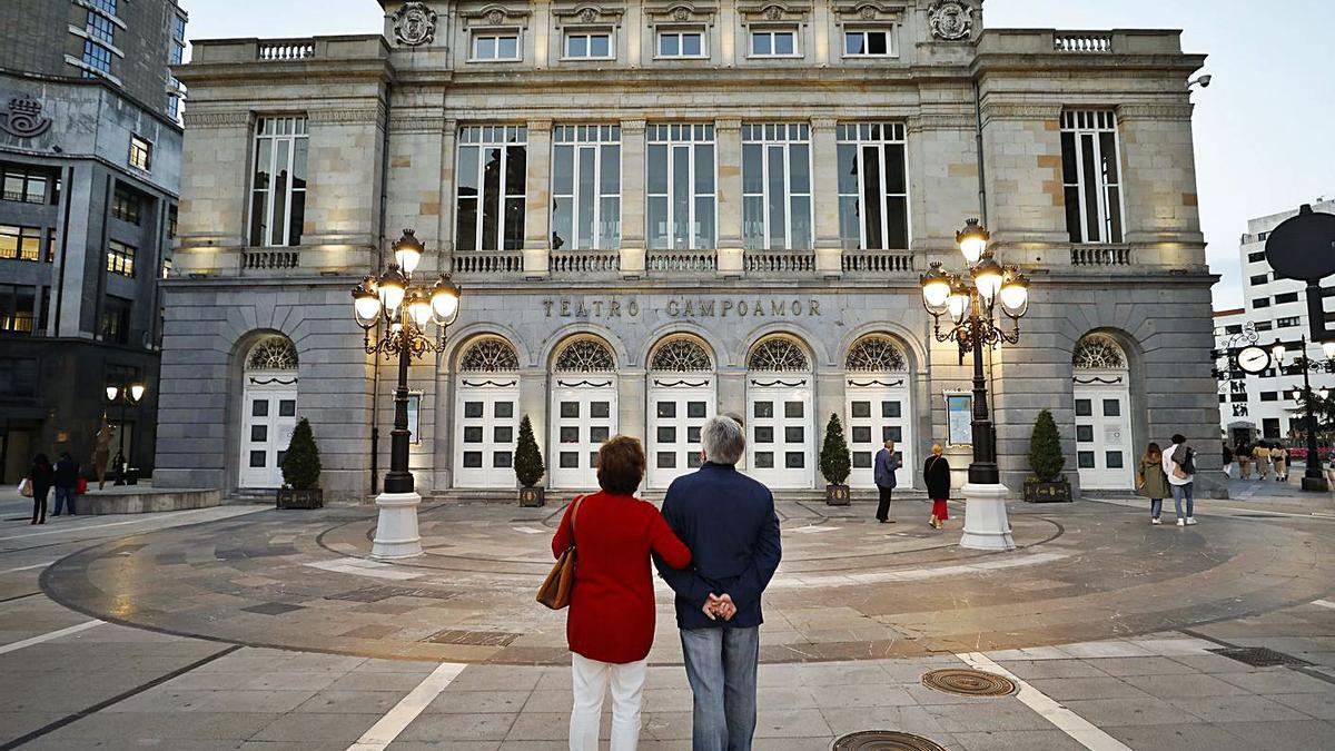 Dos paseantes observan la nueva imagen de la fachada del teatro Campoamor. | Luisma Murias