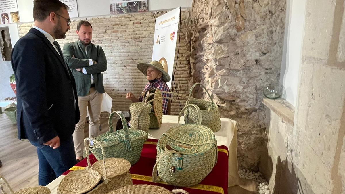 El alcalde y el vicealcalde contemplan al artesano del esparto trabajar en la Casa del Artesano.