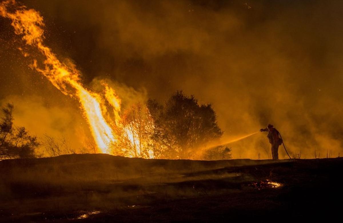 Un bomber combat l’incendi ’Rocky’, a prop de Clearlake (Califòrnia), aquest diumenge.