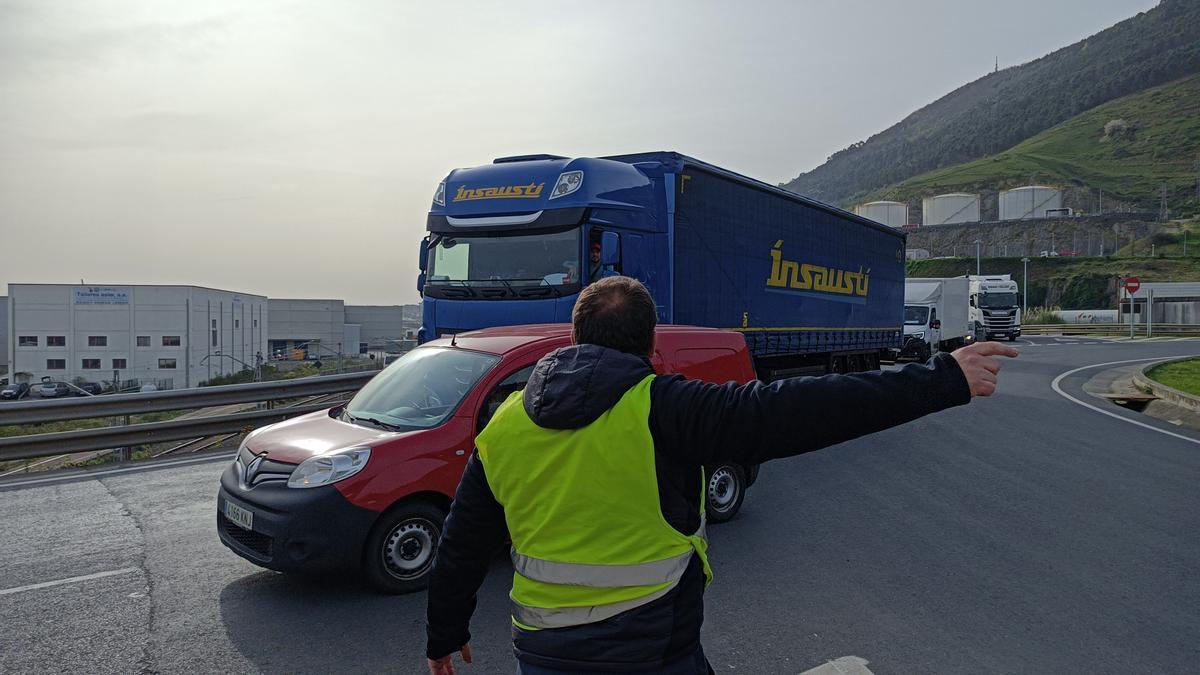 Un piquete informativo señaliza con la mano para tratar de impedir la entrada de un camión al Puerto de Bilbao.