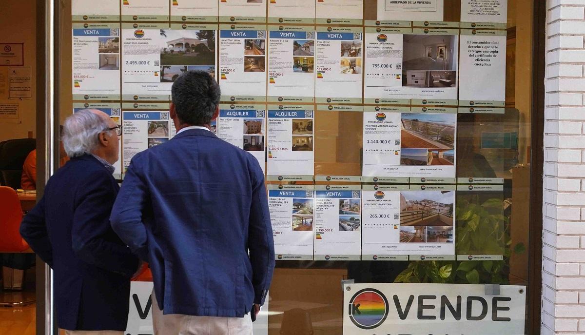 Dos personas observan un escaparate de una inmobiliaria en Málaga capital.