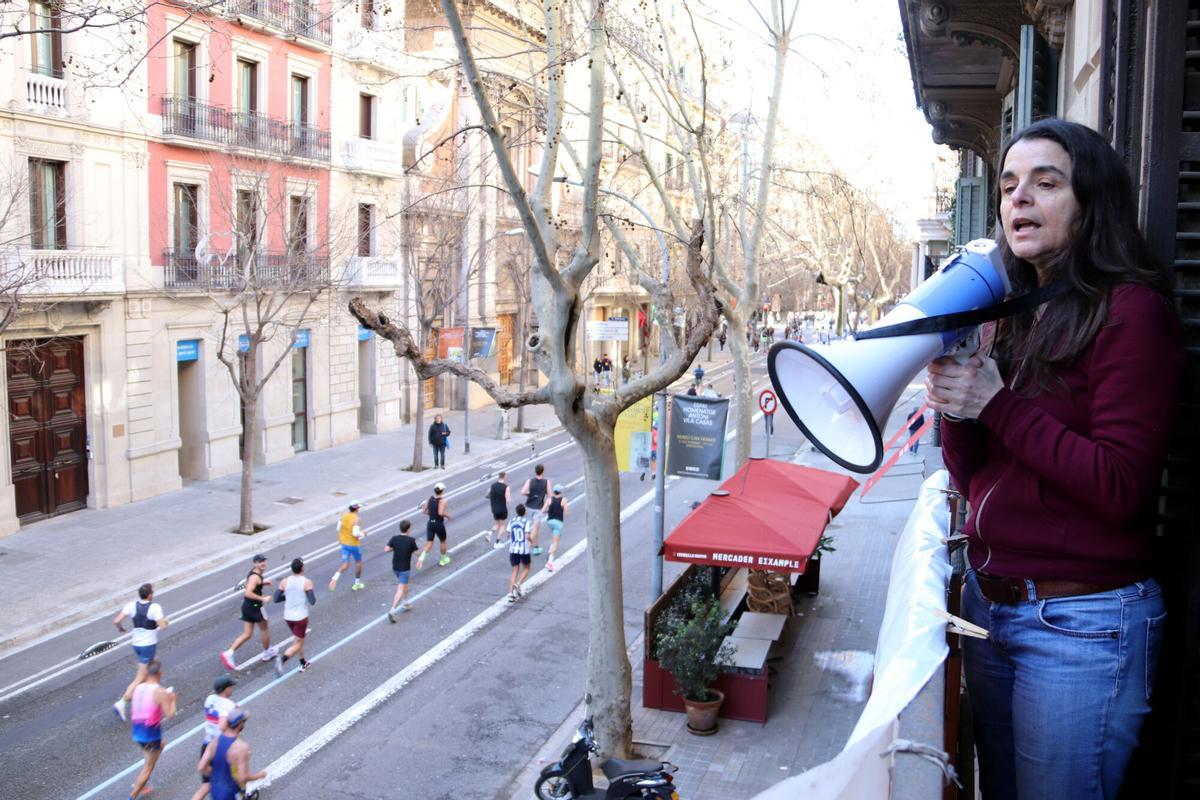 Gemma Tramullas, veïna del bloc Mallorca 243, amb un megàfon al balcó mentre passen els corredors de la Marató