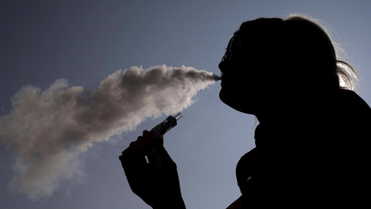 Una mujer exhala el vapor de un cigarrillo electrónico.