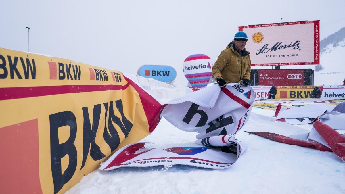 Un hombre retira los carteles publicitarios tras la cancelación de la carrera Super-G femenina en la Copa del Mundo