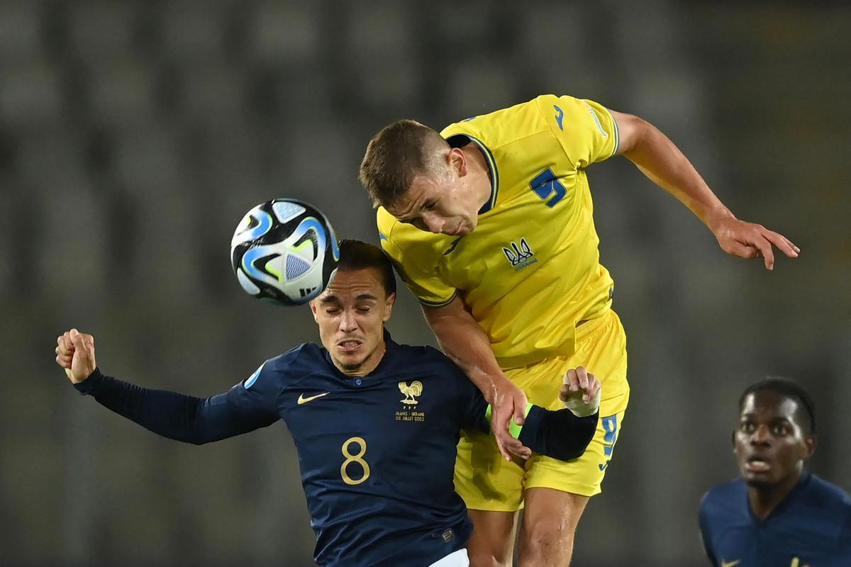 Danylo Sikan, delantero de la selección sub-21 de Ucrania, remata un balón ante el francés Maxence Caqueret.