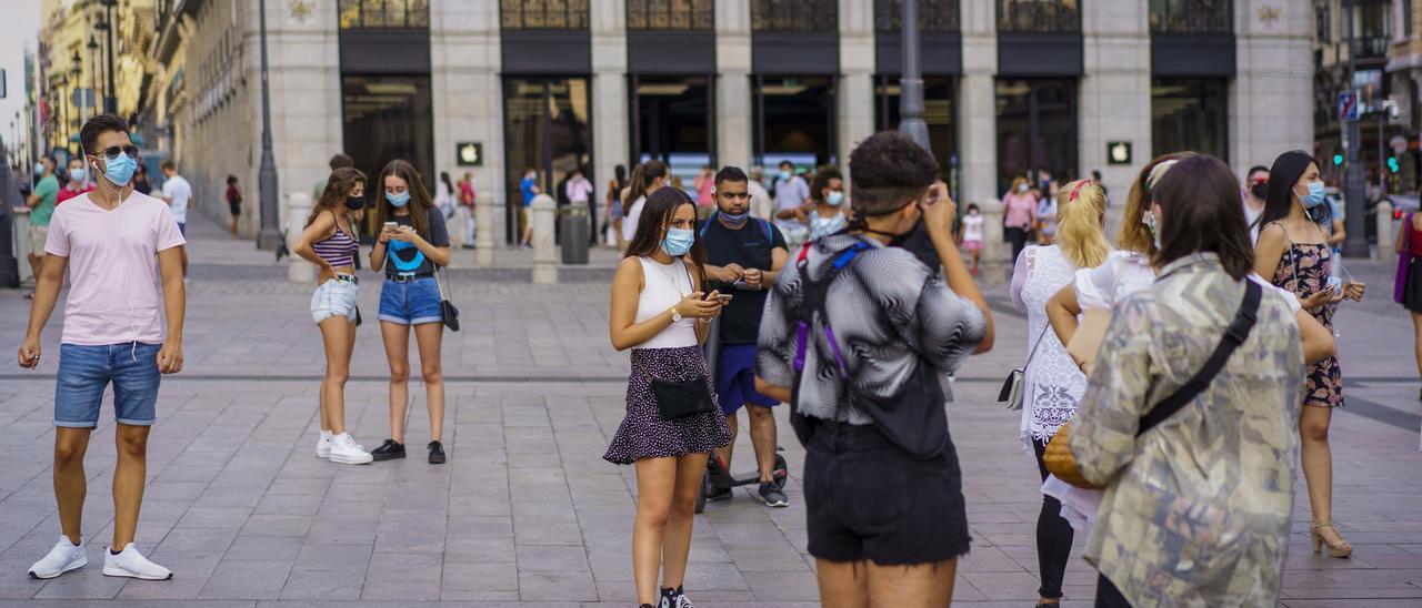 Jóvenes en la calle haciendo uso de la mascarilla.