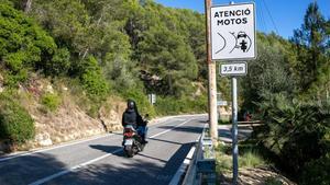 Una moto pasa al lado de una señal que avisa de las nuevas marcas en la calzada en la carretera del pantano de Foix.