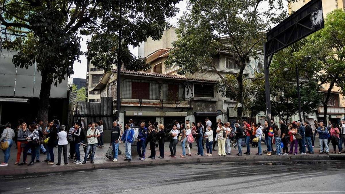 Gente hace cola en Caracas para coger el autobús.