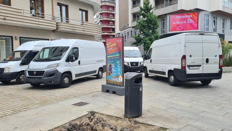 Cuatro vehículos de reparto de una empresa de mensajería, estacionados en zona peatonal.