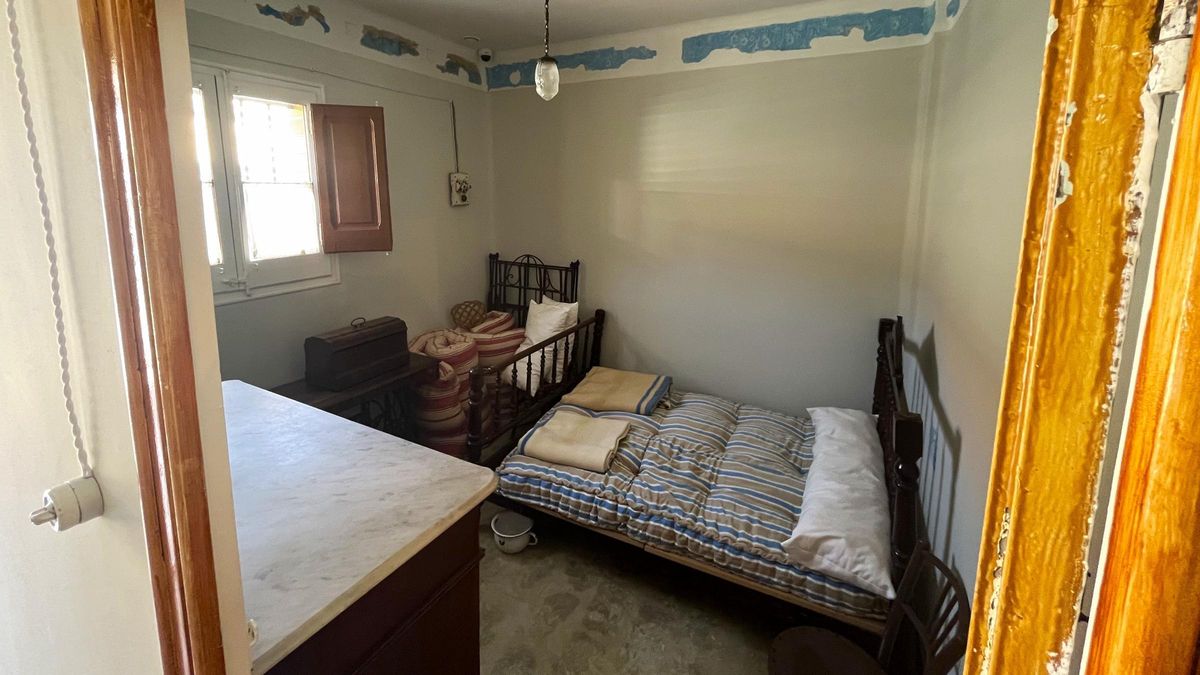 Dormitorio con colchón de borra y orinal bajo la cama.