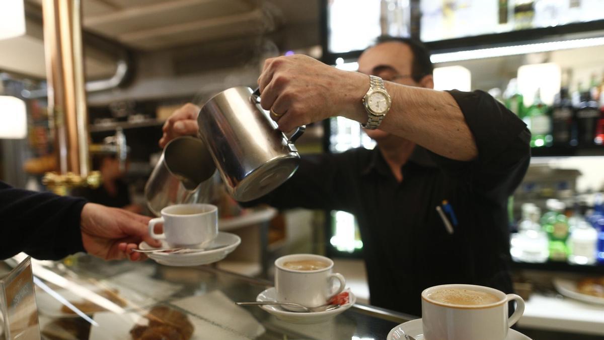 Un camarero sirve un café a sus clientes.