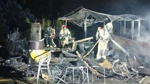 Los bomberos extinguiendo el fuego que se ha ardido en unas barracas en El Prat de Llobregat.