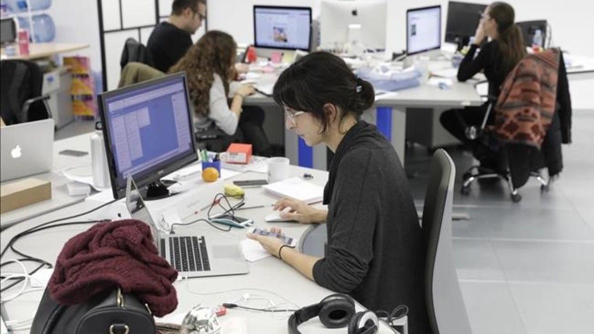 Trabajadores en una oficina frente al ordenador.