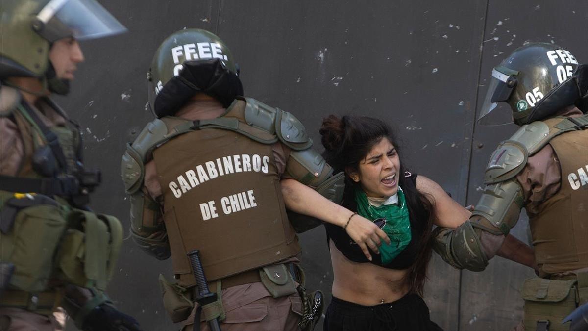 Unos carabineros se llevan detenida a una joven durante una protesta, este jueves, en Santiago de Chile.