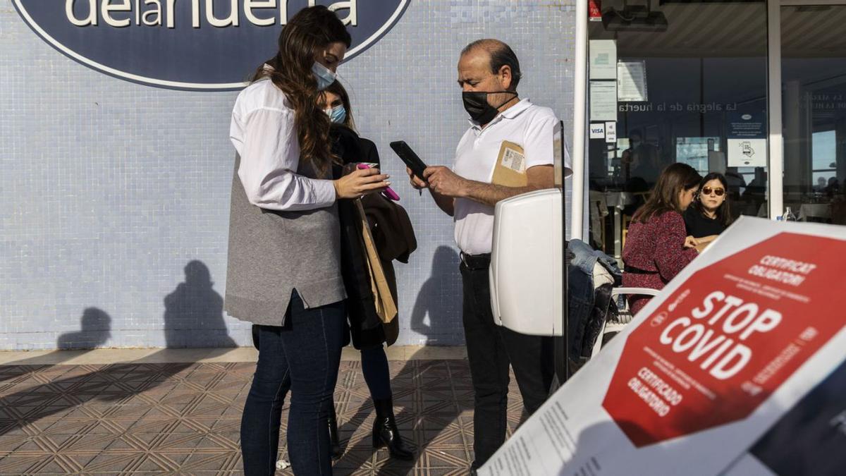 Un empleado de un restaurante en el paseo marítimo de València comprueba el pase covid. | GERMÁN CABALLERO