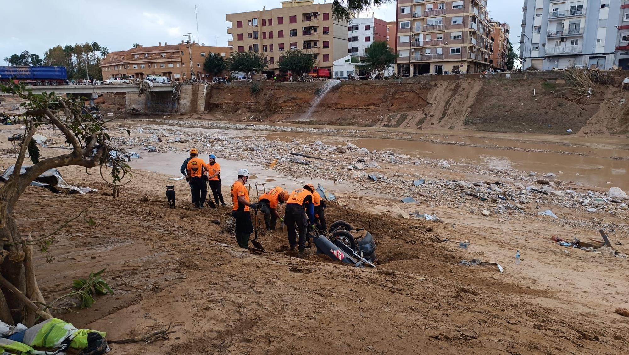 Miembros del Grupo Balear de Rescate ante un coche enterrado en Paiporta.