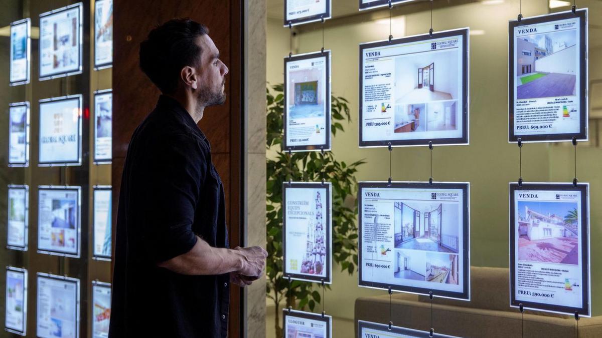 Un jove contempla pisos en venda i lloguer d’una immobiliària. | ELISENDA PONS