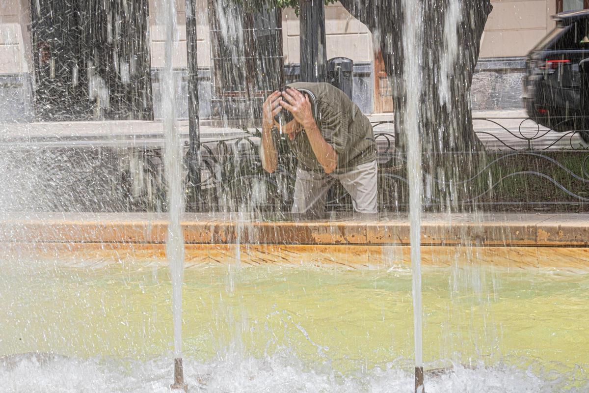 Un vecino se refresca en una fuente para sobrellevar las altas temperaturas