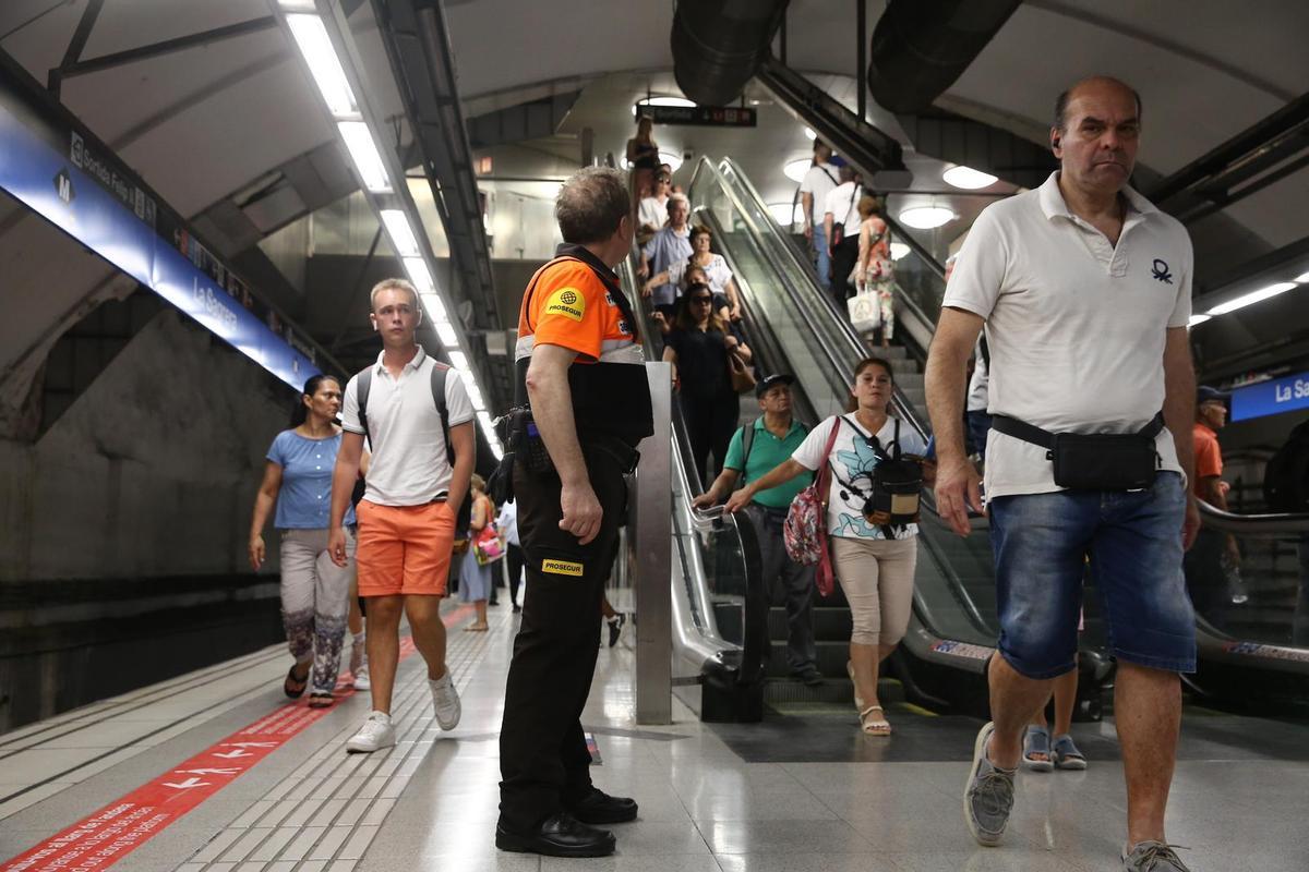 Bullicio en el andén de Sagrera, ante la atenta mirada de un vigilante del metro