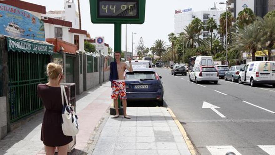 Jóvenes fotografiándose ante el termómetro con la temperatura máxima de Maspalomas, ayer. | sergio pérez