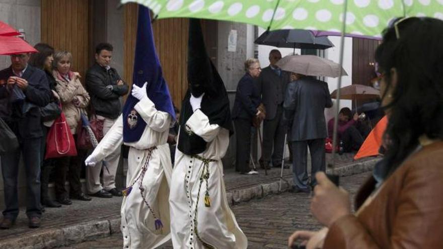 Nazarenos de la Redención, en Sevilla, bajo la lluvia.