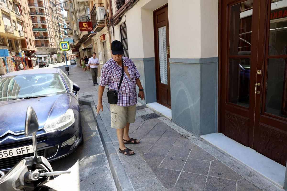 Un testigo indica el lugar de la vía pública en el que se desplomó Felipe Hernández tras salir de su tienda, malherido.