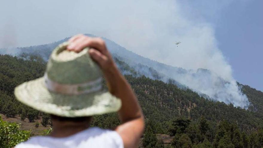 Una residente observa cómo un helicóptero arroja agua sobre el fuego. // Reuters