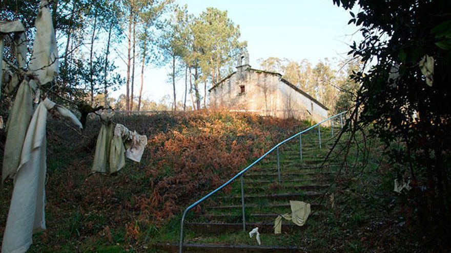 La capilla de Bendrade en lo alto y escaleras para bajar a la fuente, junto a paños colgados en las ramas de los árboles.