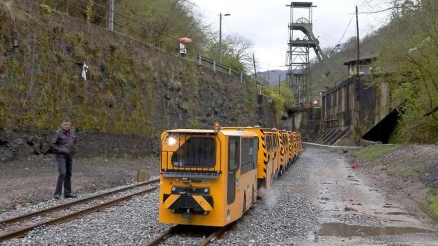 El tren turístico minero, con el castillete del pozo Samuño al fondo, regresa a El Cadavíu en su primer viaje de prueba.