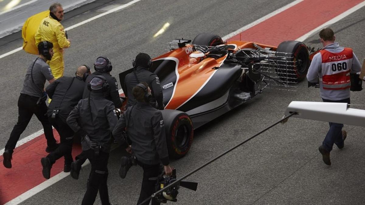 Los mecánicos de McLaren empujan el coche de Vandoorme tras pararse en Montmeló.