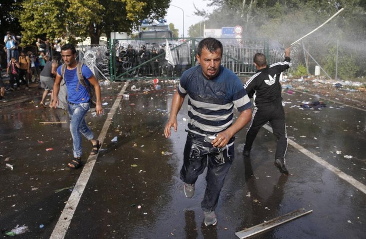 Refugiados sirios escapan ante el uso de gases lacrimógenos por parte de fuerzas antidisturbios de Hungría, en la frontera con Serbia.
