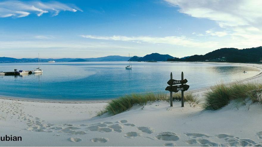 Las Cíes de Lubián. Abrimos agosto con esta foto de inmensa belleza de las Cíes y su playa de Rodas hecha por el fotógrafo vigués Alfonso Lubián, y que en esta primavera cumplió 20 años de su realización, siendo de las más publicadas por empresas (y más pirateadas, dice el autor). No sé si la tomó desde el aire, pero podría. Lubián es el más experimentado conductor aéreo como primer piloto de la comunidad que dirigió un globo, y montó una empresa ofreciendo a incontables personas esa experiencia. Este año, cumplidos los 70, cerró la misma para descansar, pero mirad qué foto nos ha dejado.