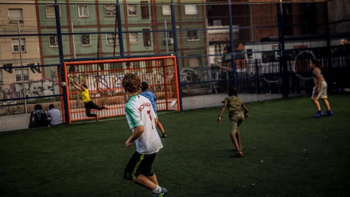 Niños juegan a fútbol en la pista del parque de La Granada de L'Hospitalet de Llobregat, en el marco del proyecto 'Espais Oberts per un Estiu Enriquit'.