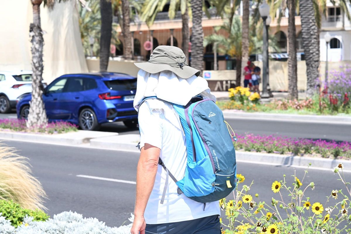Un hombre con un sombrero y una toalla para protegerse del sol.