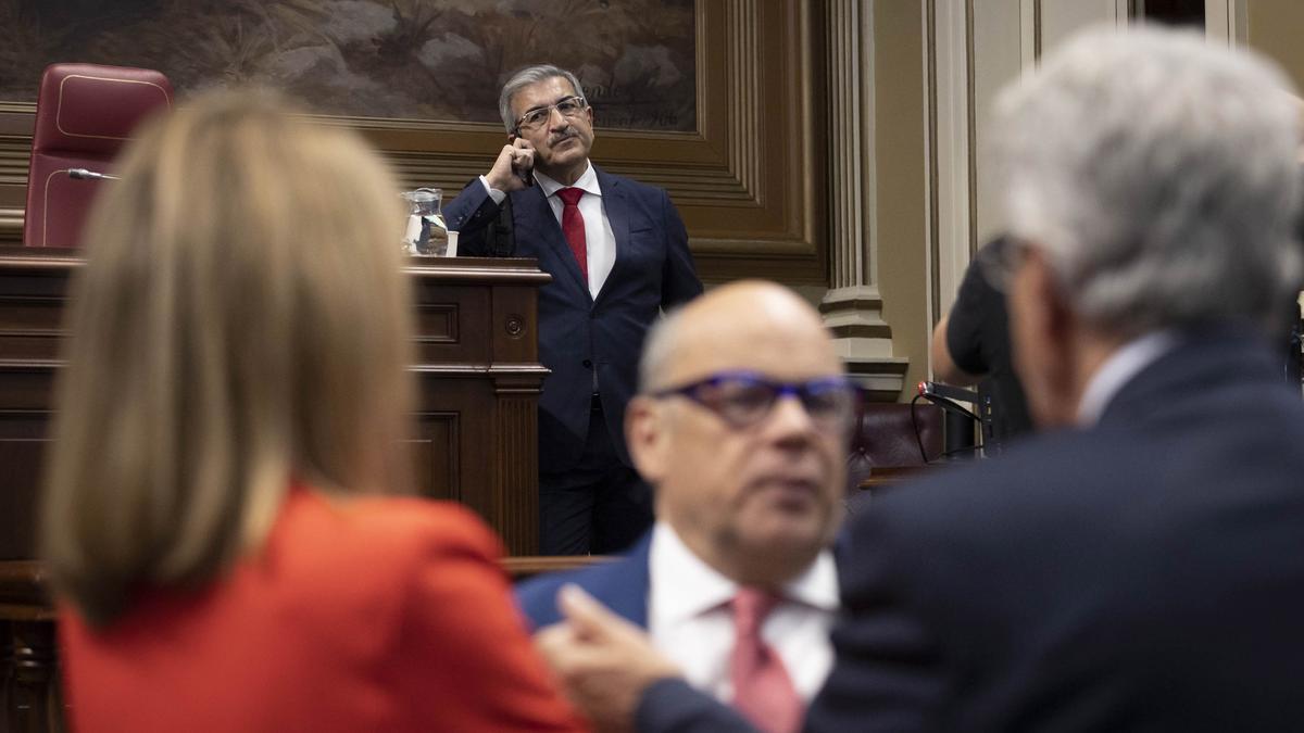 Román Rodríguez habla por teléfono momentos antes del pleno de este martes en el Parlamento de Canarias.