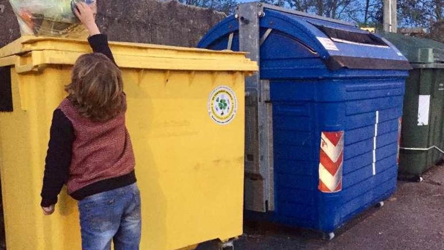 Un niño deposita una bolsa de basura en un contenedor de Tomiño.