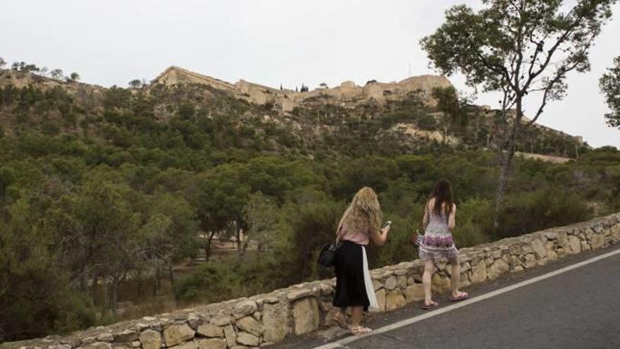 Dos turistas suben ayer por la carretera del Monte Benacantil hacia el Castillo de Santa Bárbara, donde el 24 de junio se dispara la palmera.