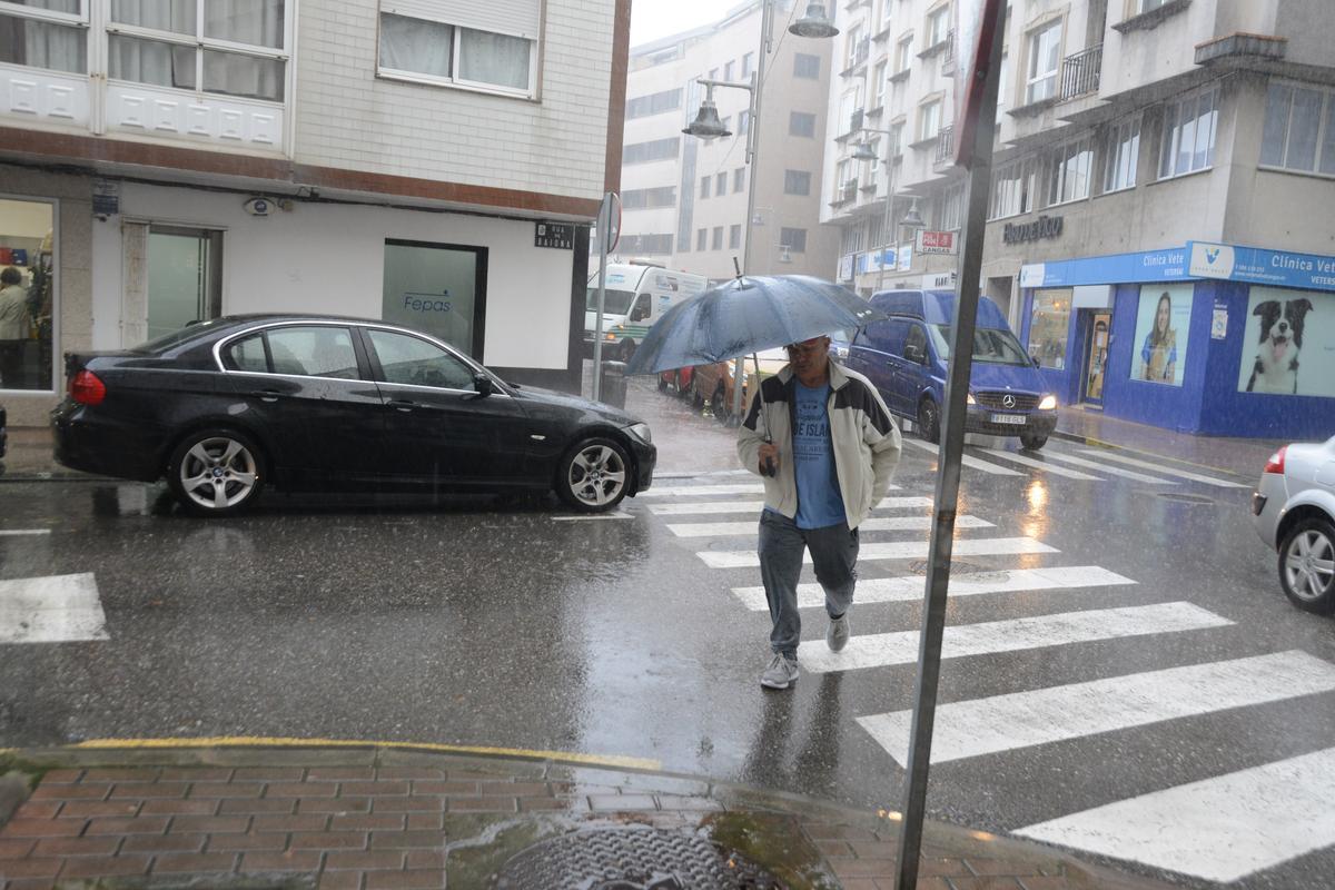 Un vecino camina por la calle Baiona, en Cangas, protegiéndose de la lluvia con un paraguas.