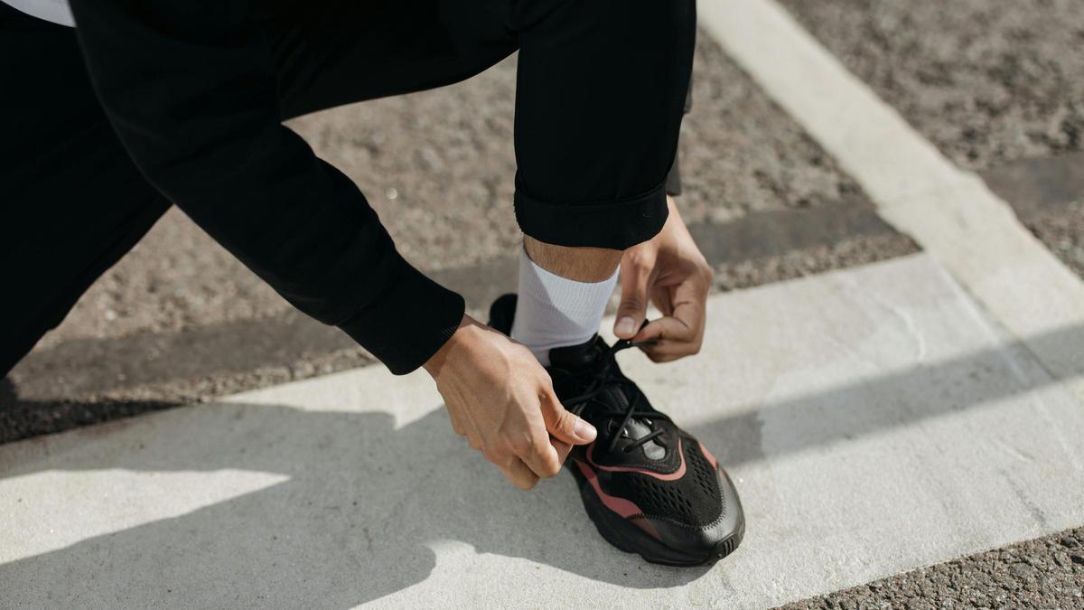 Una persona atándose las zapatillas deportivas.
