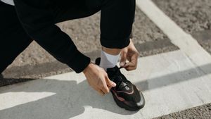 Una persona atándose las zapatillas deportivas.
