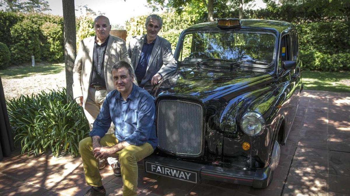 Tres de los diseñadores del nuevo taxi eléctrico de Londres: Rafa Sanchis (sentado), Josep Maria Solé (centro) y David Ancona, delante de un modelo de los 80.