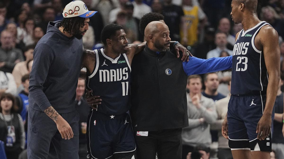 Anthony Davis y un asistente de los Mavs ayudan a su compañero Kyrie Irving a abandonar la pista tras sufrir un alesión de ligamento cruzado anterior.
