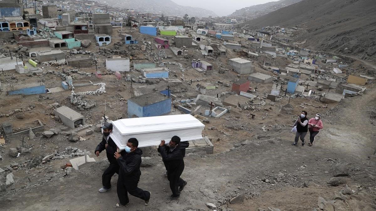 Trabajadores de un cementerio de Lima portan el féretro de un fallecido por covid, el miércoles pasado.