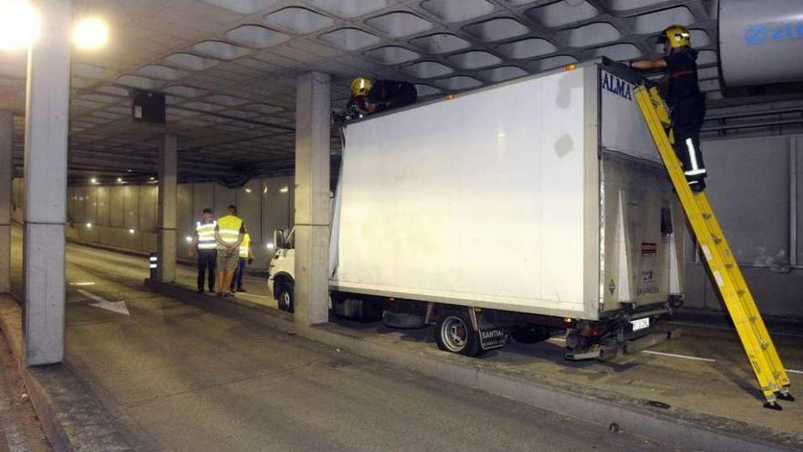 Policías y bomberos intervienen para desatascar el camión en el túnel de María Pita.