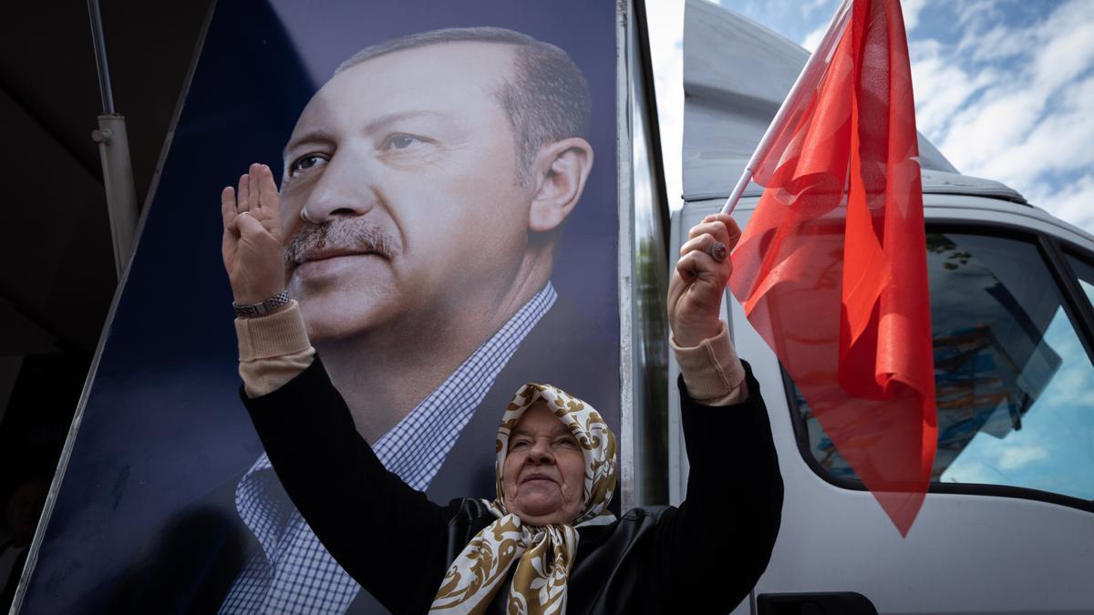 Una mujer turca ondea una bandera junto a un inmenso retrato de Erdogan.
