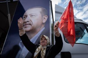 Una mujer turca ondea una bandera junto a un inmenso retrato de Erdogan.