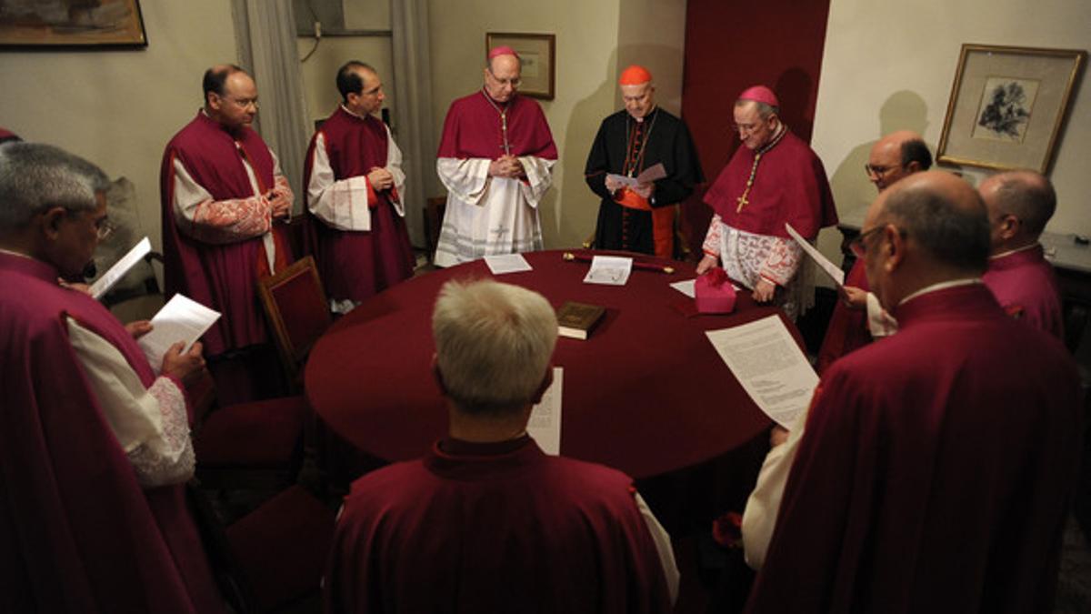 El cardenal Tarsicio Bertone (centro) da fe de la situación de sede vacante del Vaticano antes de sellar la residencia del Papa, el jueves.